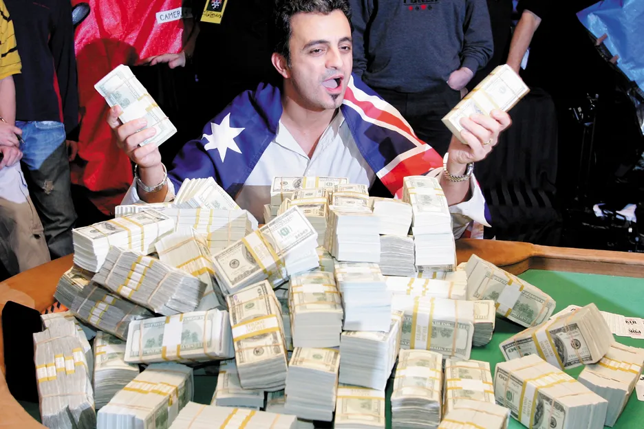 Joe Hachem poses with piles of cash at the WSOP